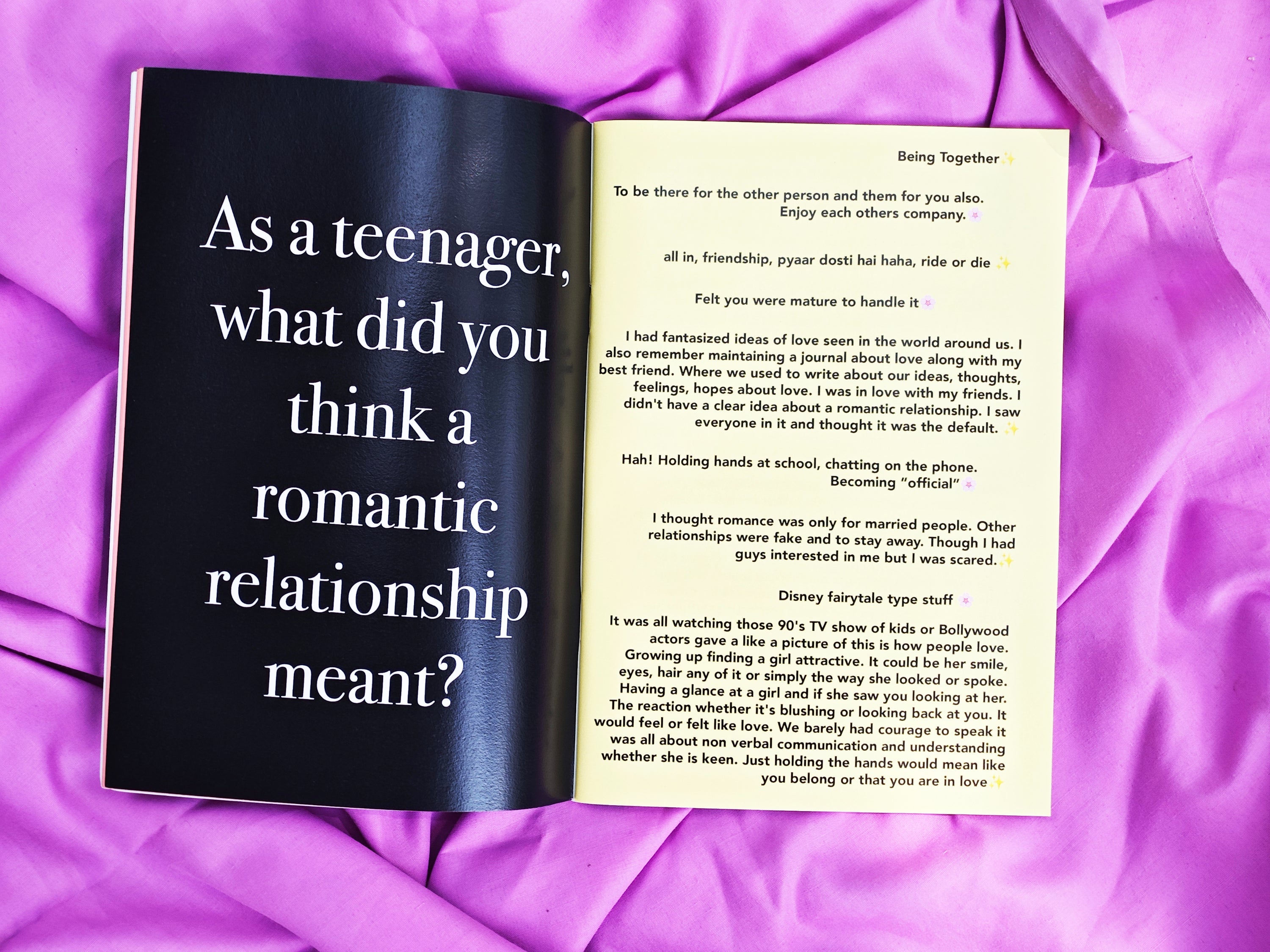 Open spread of "On Loving & Love" — left cream page with collected responses about teenage romantic relationships, right black page with large white serif text "As a teenager, what did you think a romantic relationship meant?", on purple satin fabric