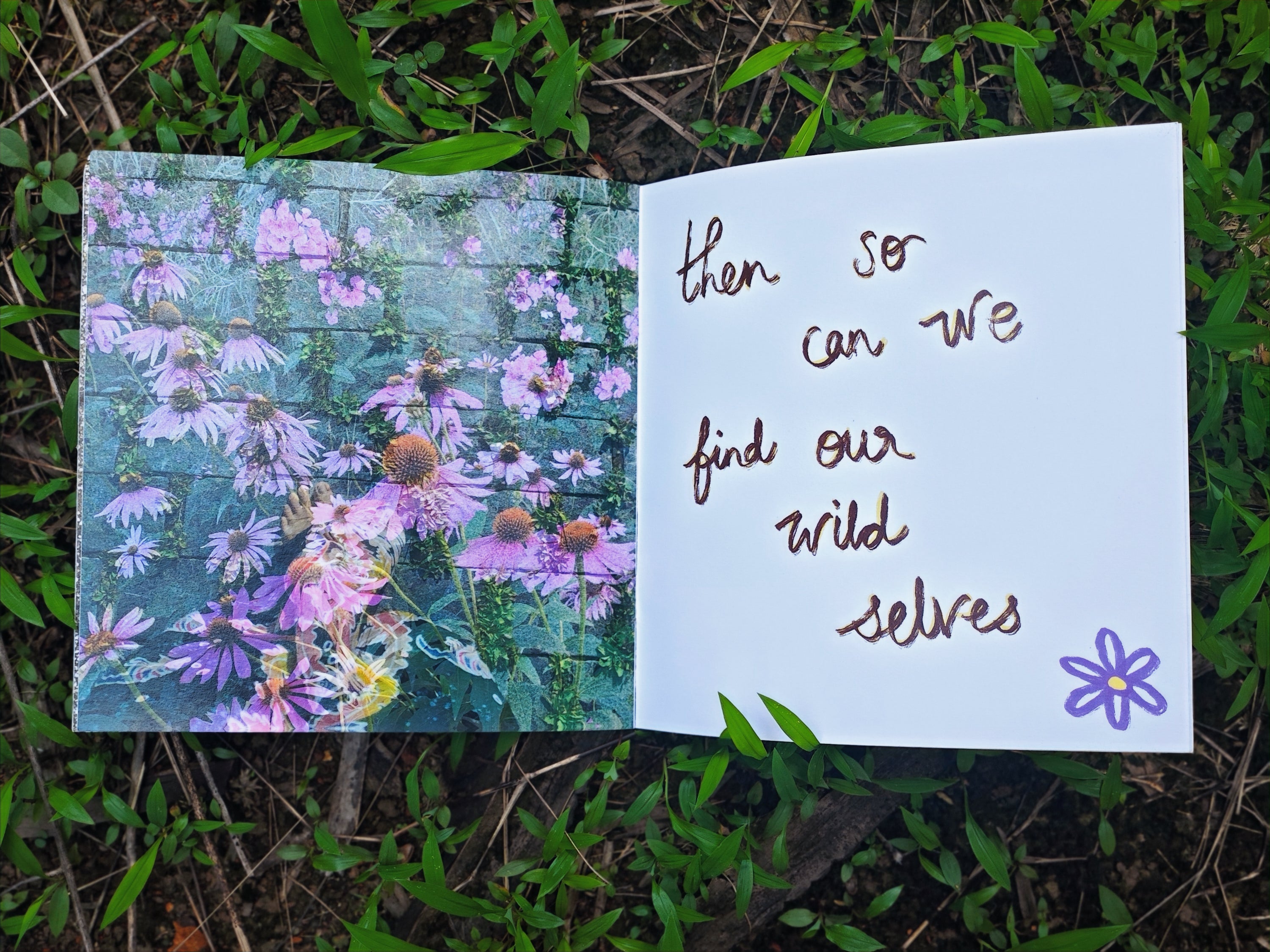 Open spread on grass — left page with photograph of pink and purple wildflowers growing through a wall, right page with handwritten text "then so can we find our wild selves" and small purple flower doodle