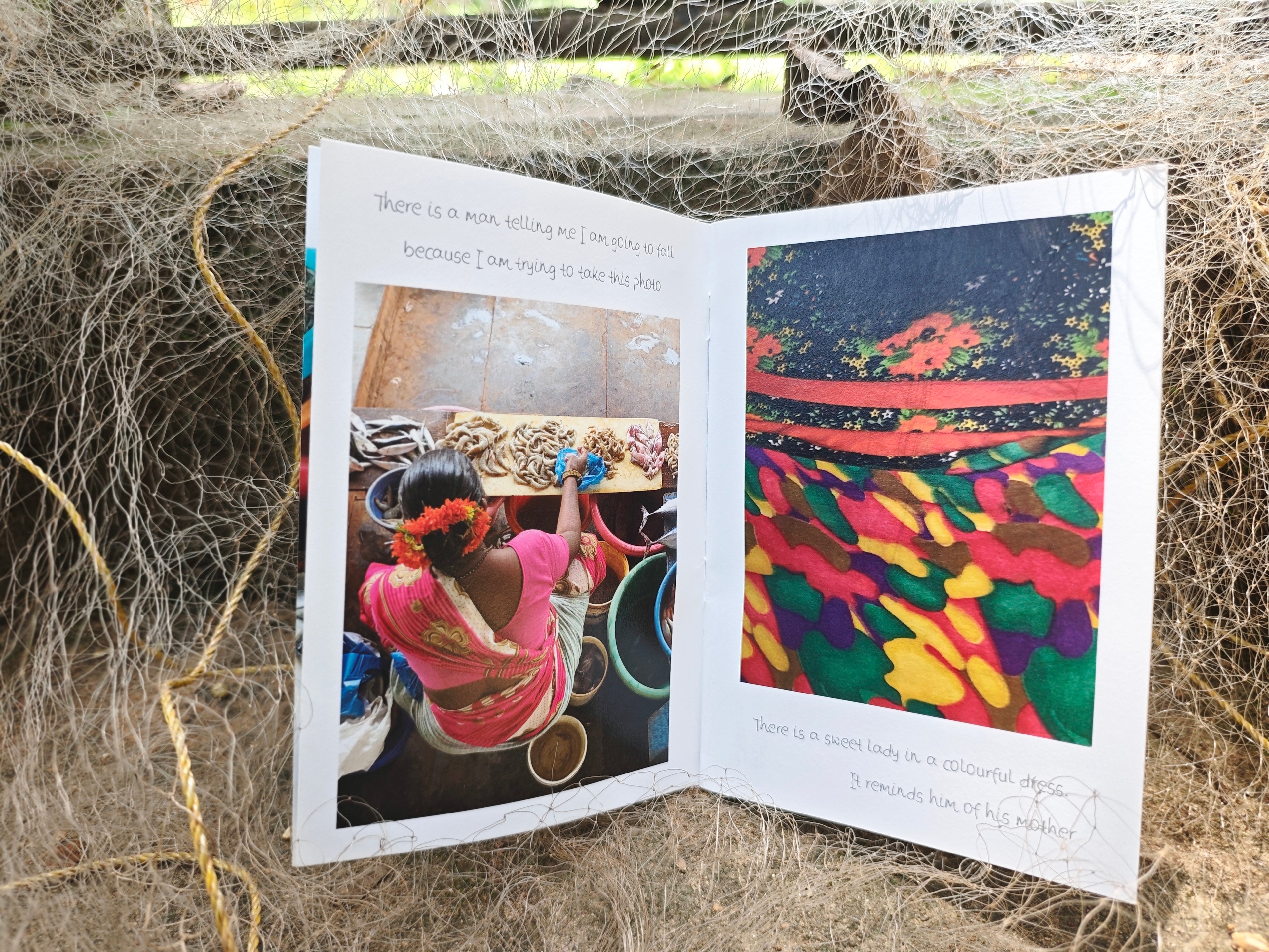 Open spread — left page shows a woman in pink sari at a market stall with handwritten text, right page shows colourful patterned fabric close-up, nestled in fishing nets